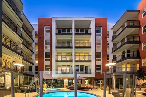 A modern apartment building with a pool in the courtyard.