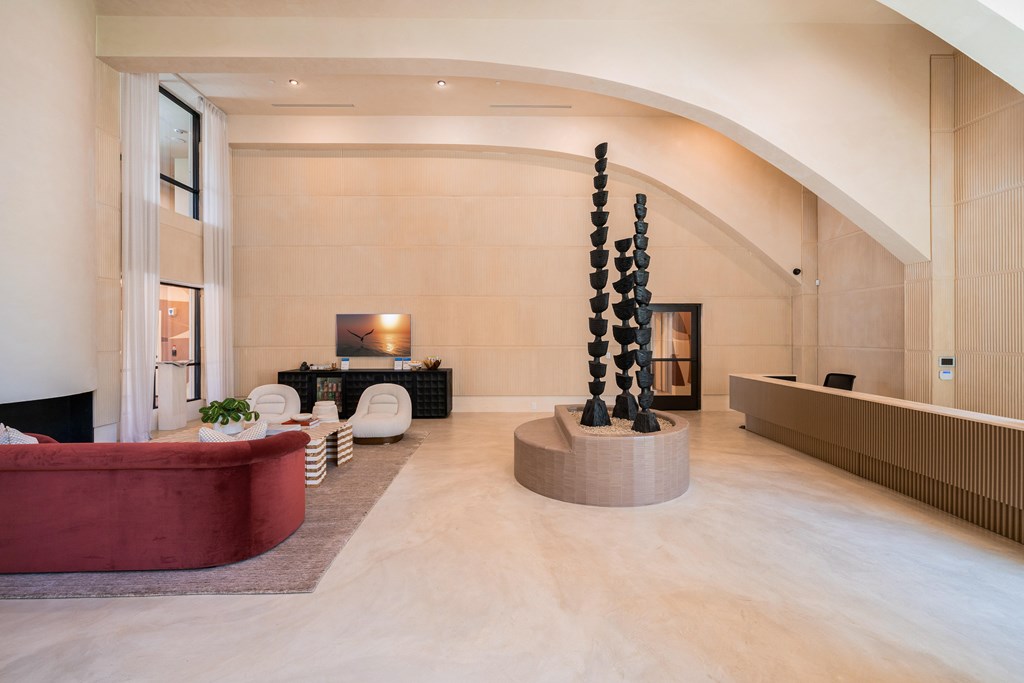 A living room with a red couch and a large sculpture.