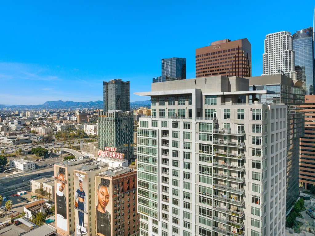 A cityscape with a large building in the foreground and a clear blue sky above.