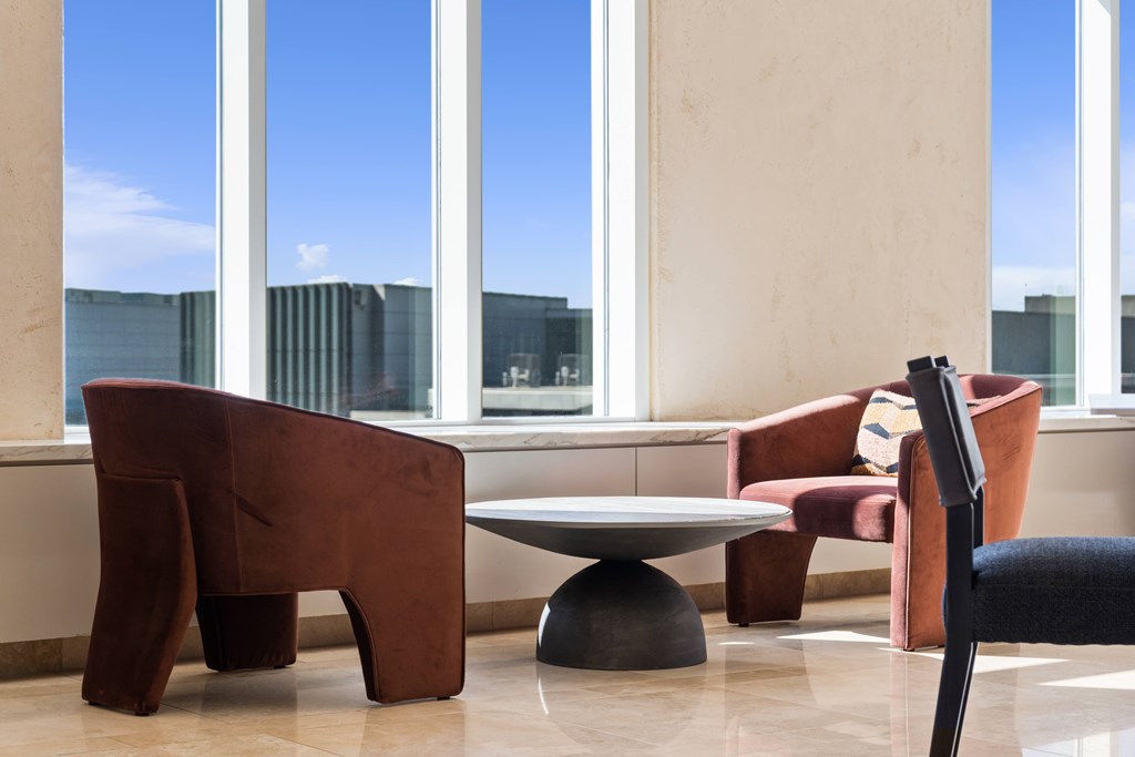 A room with a brown chair and a table in front of a window.