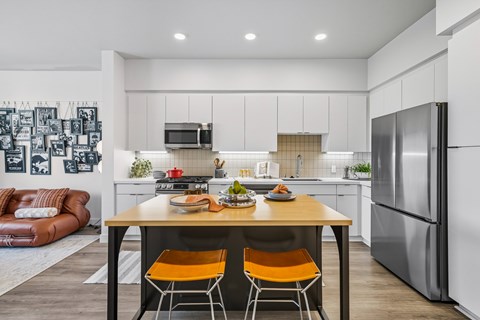 A modern kitchen with a wooden table and orange chairs.