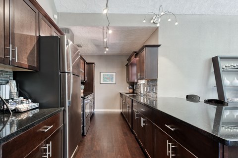 a kitchen with black counters and stainless steel appliances and wooden cabinets