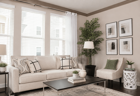 A living room with a white couch, a green plant, and a white lamp.