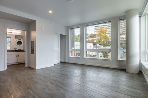 A large empty room with a washer and dryer in the kitchen area.