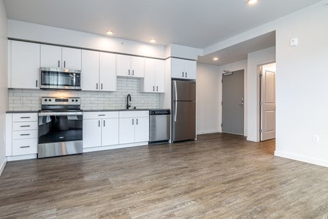 A kitchen with white cabinets and a wooden floor.