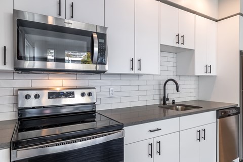 A modern kitchen with a stainless steel oven and white cabinets.