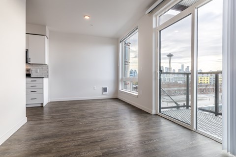 A room with a wooden floor and a view of the city through a glass door.