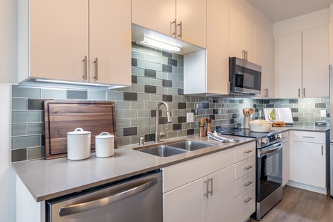 A kitchen with white cabinets and a stainless steel dishwasher.