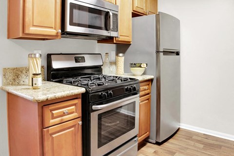 A kitchen with a stove, refrigerator, and microwave.