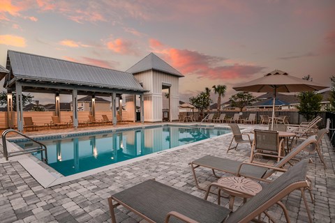 a resort style pool with lounge chairs and umbrellas