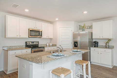 A kitchen with white cabinets and granite countertops.