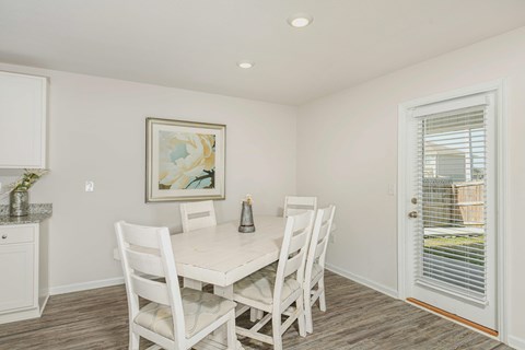 A dining room with a white table and chairs.