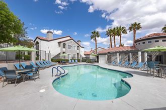 a resort style pool with lounge chairs and umbrellas