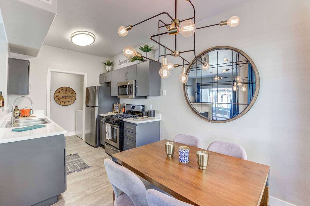 a dining area with a table and chairs and a kitchen in the background