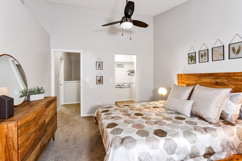 A bedroom with a bed, a dresser, and a ceiling fan.