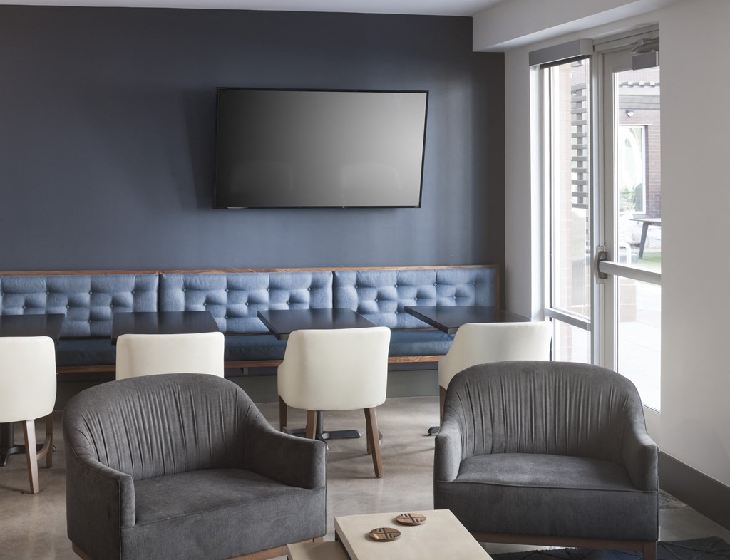 a living room with two gray chairs and a blue couch in the background and a coffee table