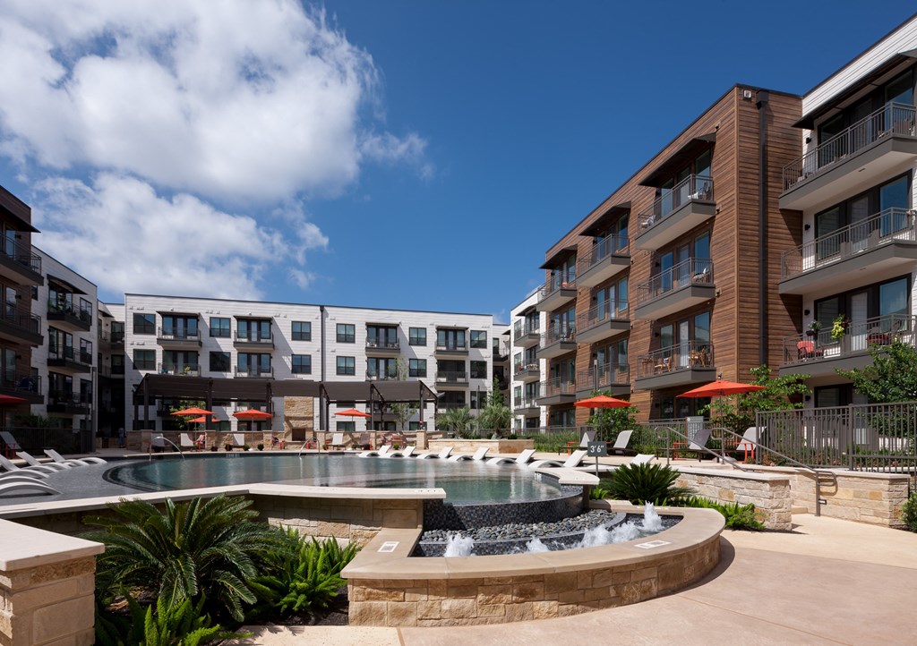 a pool with a fountain in front of an apartment building