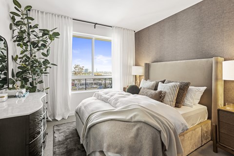 A well-lit bedroom with a large bed and a view of the city.