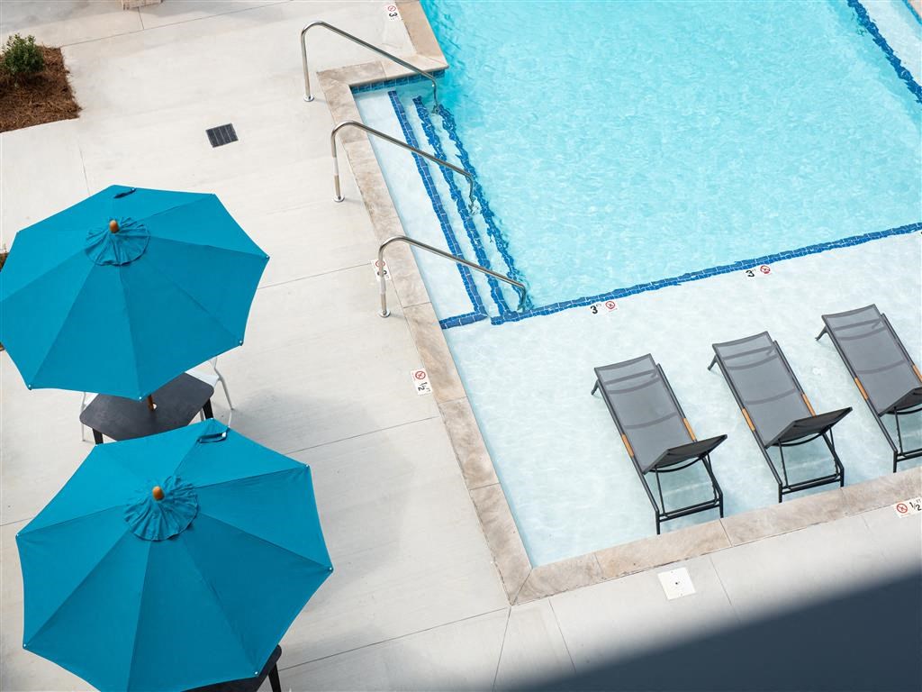 a swimming pool with blue umbrellas and chairs
