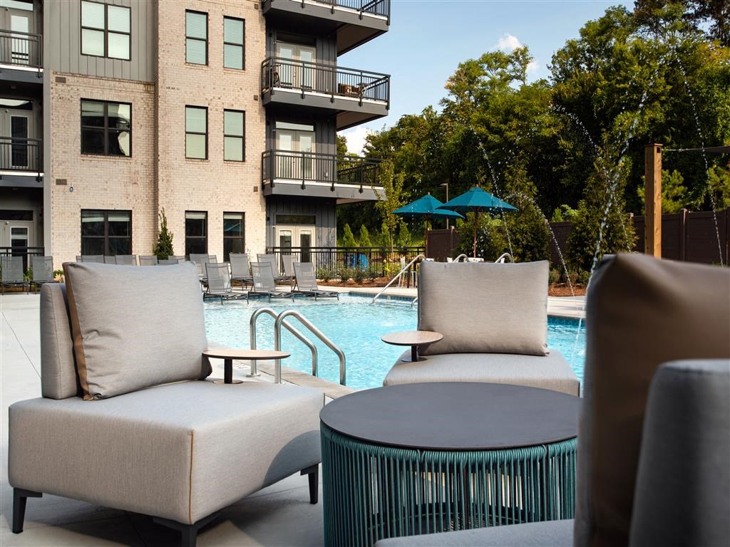 a pool with chairs and a table in front of a building