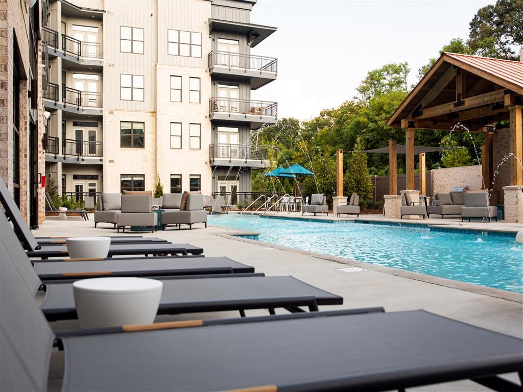 a pool with tables and chairs next to a building