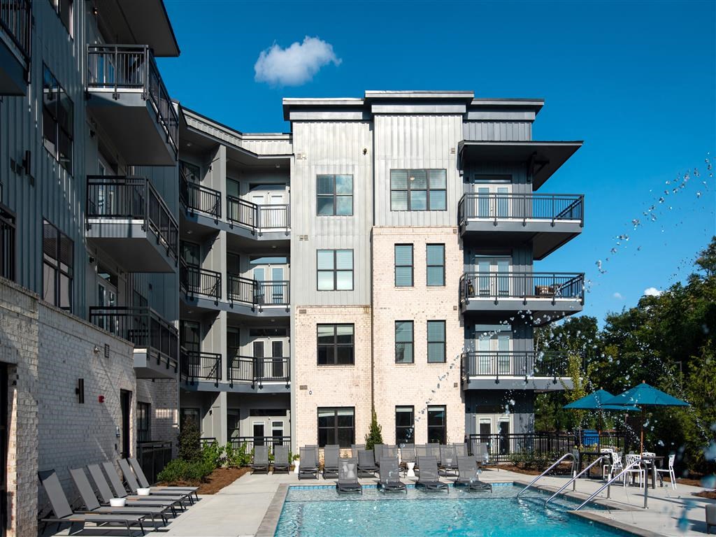 an apartment building with a pool and chairs in front of it