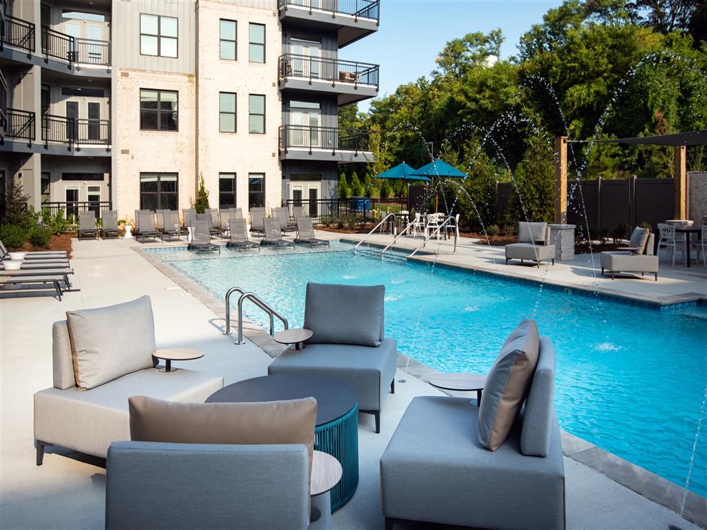 a pool with chairs and a table next to a building