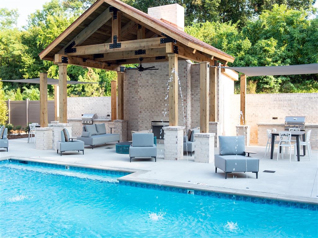 a poolside pavilion with chairs and tables next to a pool