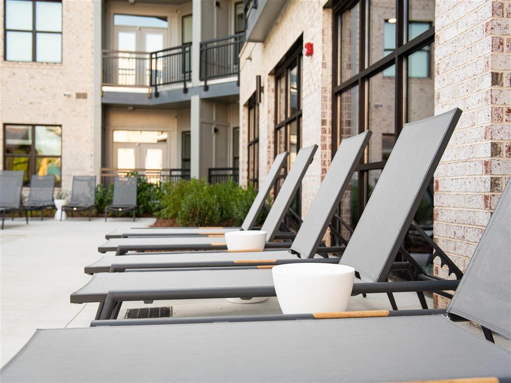 a row of lounge chairs outside of an apartment building