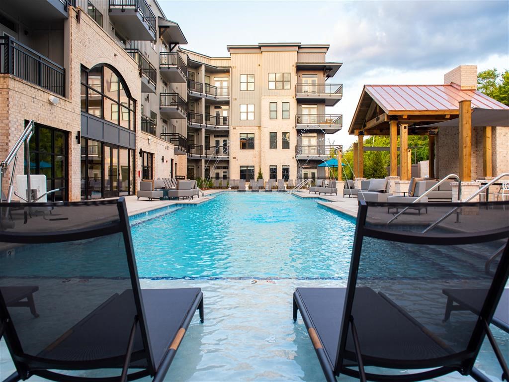 a swimming pool with chairs and an apartment building