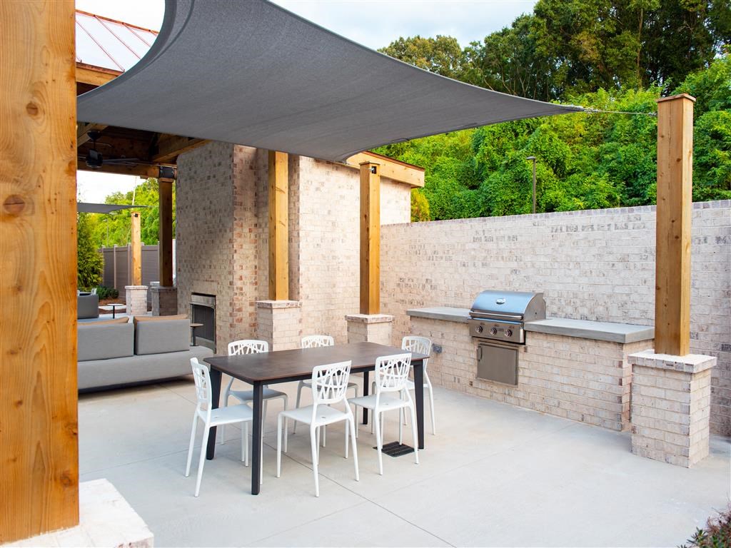a patio with a table and chairs and a barbecue grill