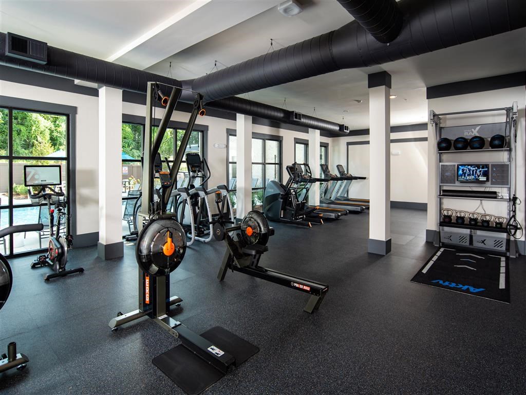 a gym with weights and other exercise equipment in a building with windows