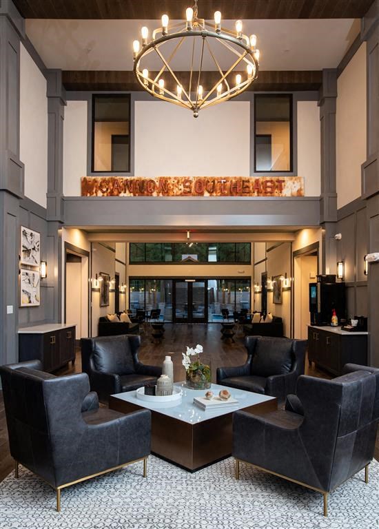a large lobby with chairs a table and a chandelier