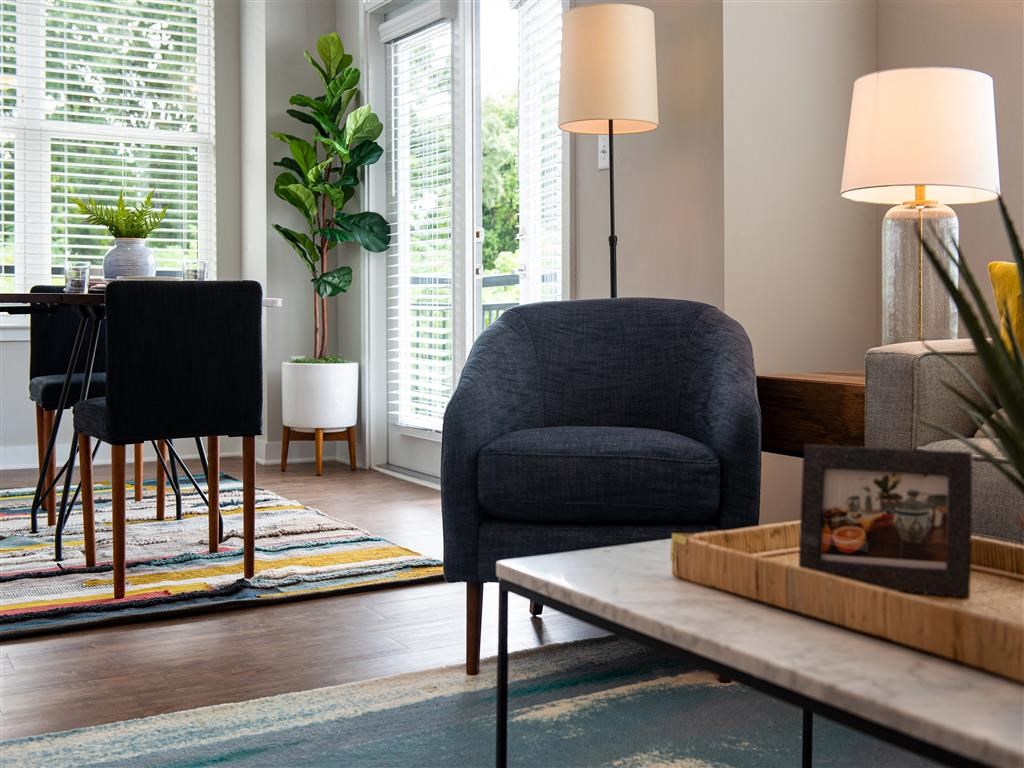 a living room with a blue chair and a dining room table