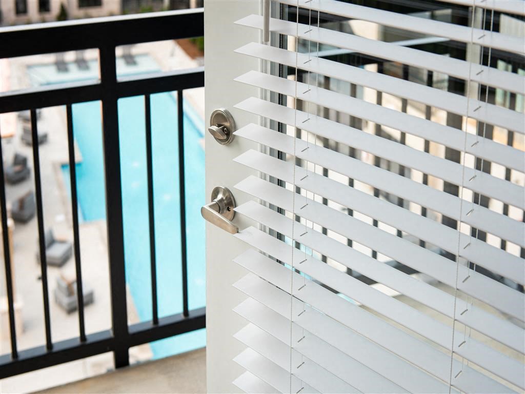 a close up of a window with white blinds on a balcony