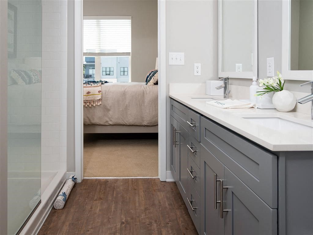 a bathroom with a sink and a shower and a bedroom
