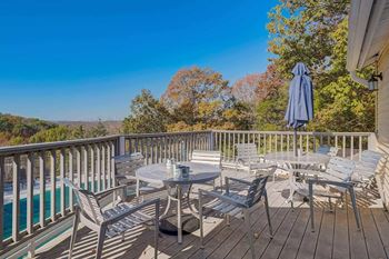 A wooden deck with a table and chairs overlooking a pool.