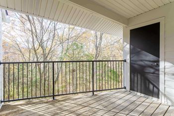 A balcony with a black railing and a wooden floor.