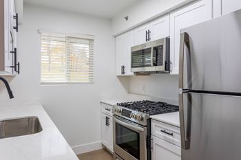 A kitchen with white cabinets and a stainless steel refrigerator.