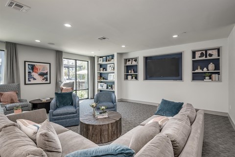A living room with a grey couch and a television on the wall.