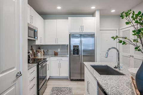 A kitchen with white cabinets and a granite countertop.