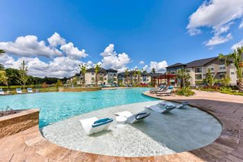 a resort style pool with lounge chairs in front of an apartment building