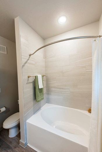 a bathroom with a tub and a toilet and a shower curtain