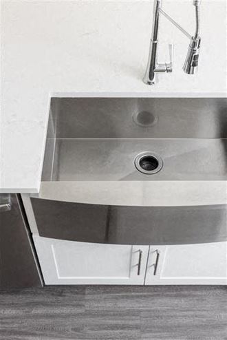 a stainless steel sink in a kitchen with white cabinets
