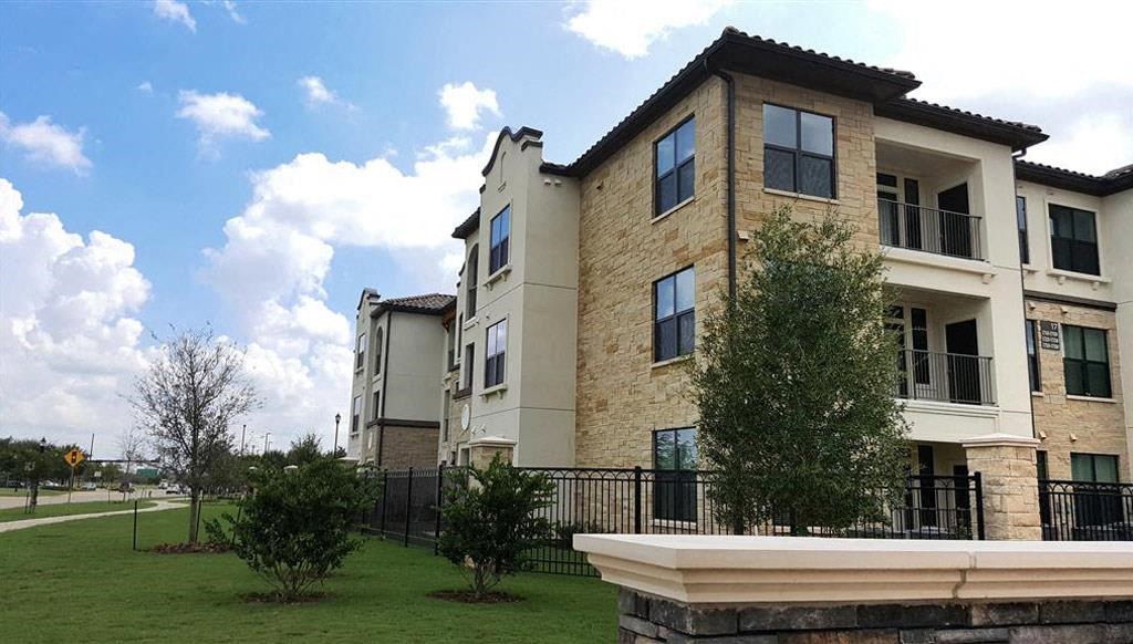 an apartment building with a green lawn and a fence