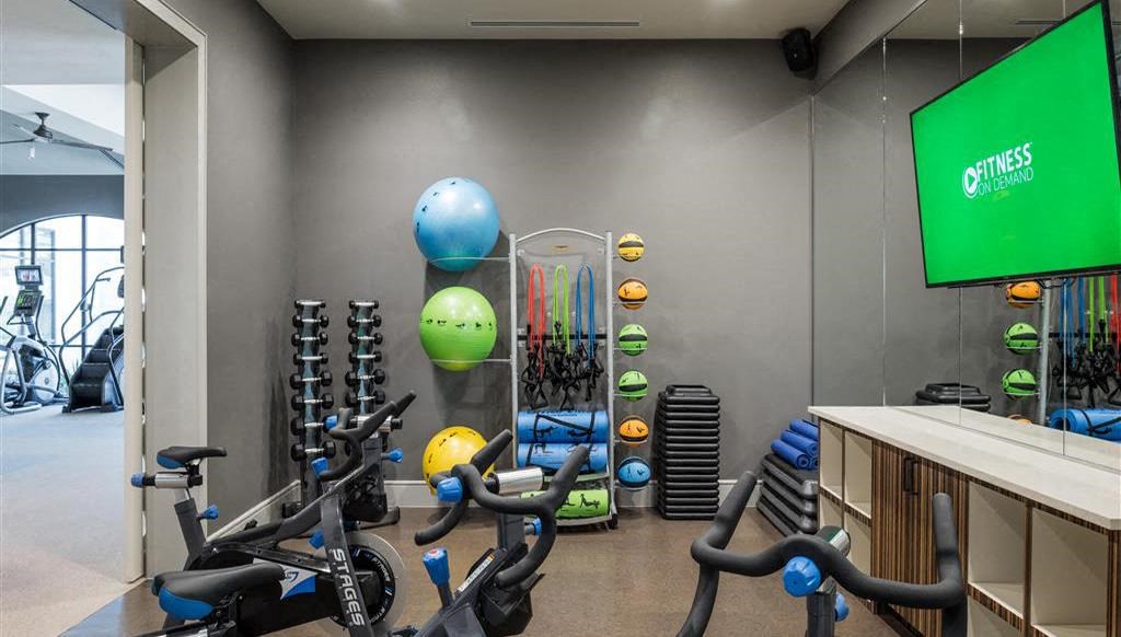 a gym with exercise equipment and a green screen