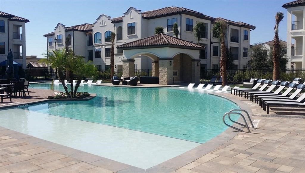 a large swimming pool with chairs in front of an apartment building