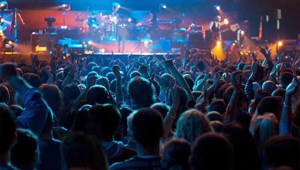 a crowd of people at a concert with their hands up