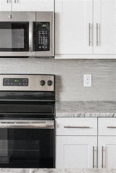 a kitchen with a stove and microwave and white cabinets