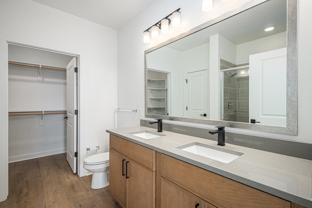 A bathroom with a toilet, sink, and mirror.